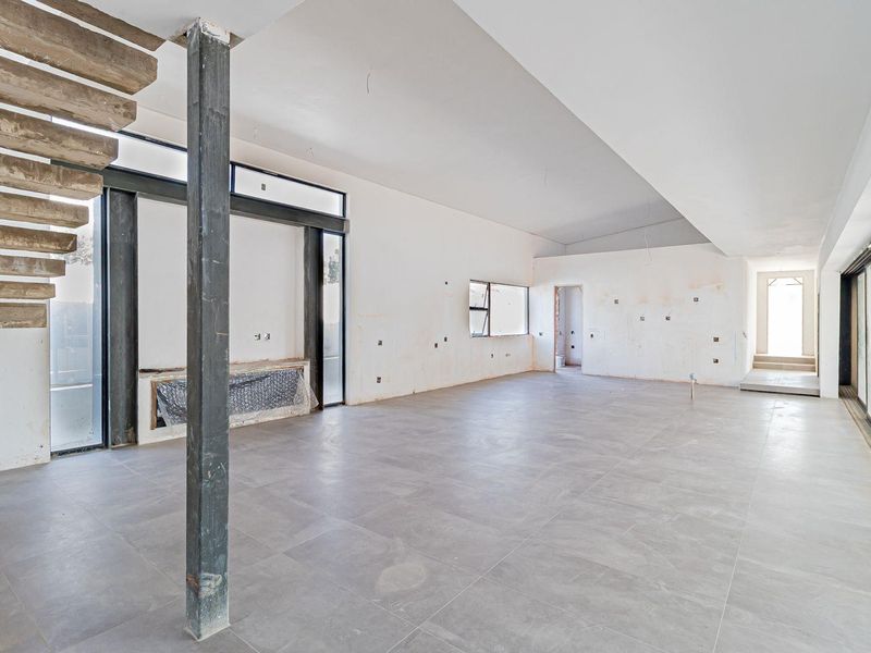 Spacious open-plan living area under construction, featuring large format floor tiles, a modern floating staircase, and expansive sliding glass doors for natural light.