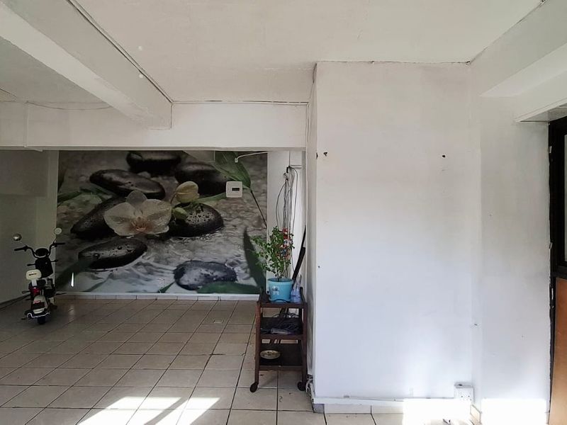An open-plan office space featuring tiled flooring, exposed ceiling beams, and a large feature wall mural, offering a versatile layout for business use.