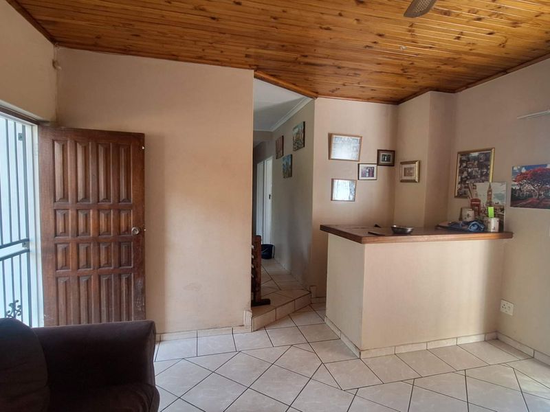 Living area featuring a built-in bar counter, timber ceiling, and tiled flooring with access to exterior security gates.