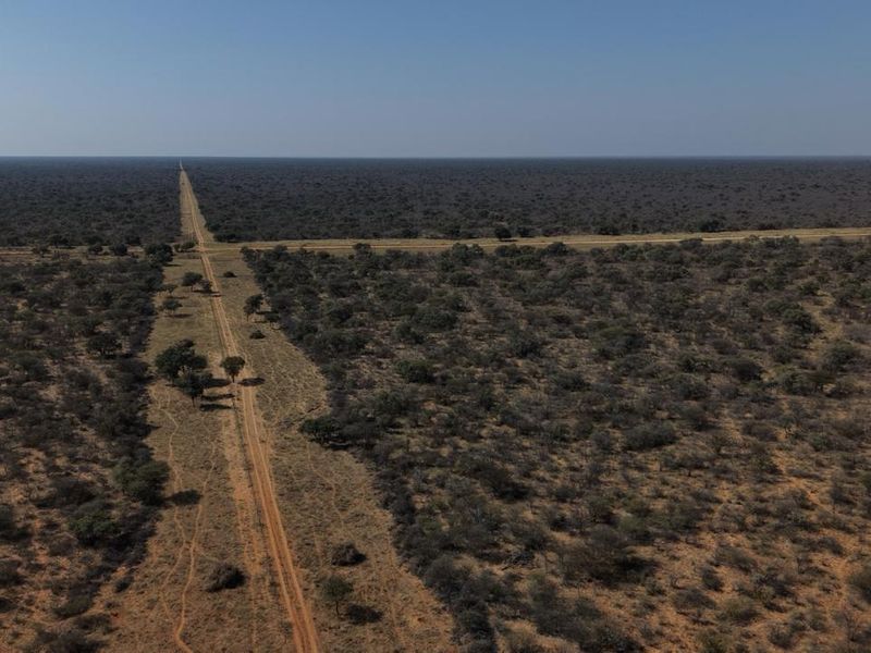 An aerial view of the expansive farm landscape featuring intersecting dirt roads and surrounding natural bushveld vegetation.