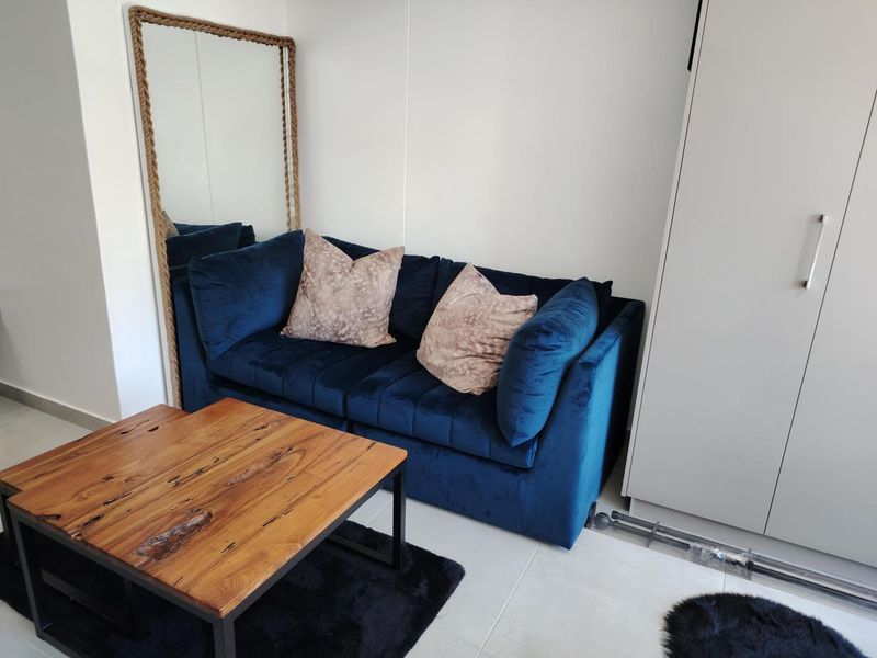 A compact living area featuring neutral tiled flooring and a built-in wardrobe, providing functional storage space within the apartment.