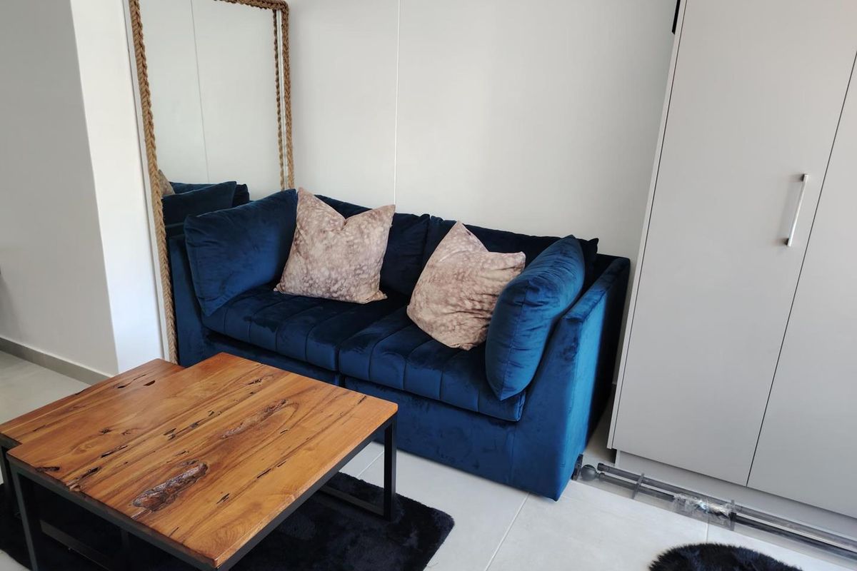 A compact living area featuring neutral tiled flooring and a built-in wardrobe, providing functional storage space within the apartment.