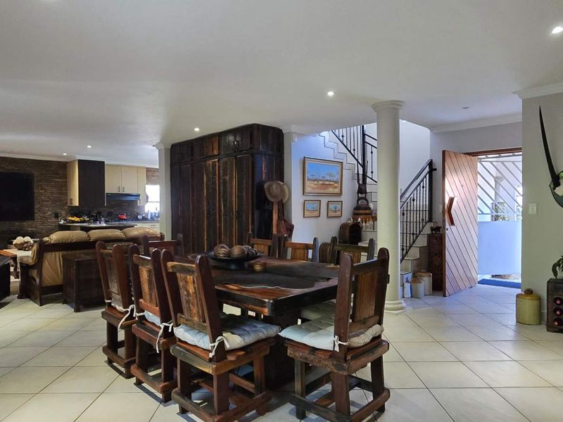 Spacious open-plan living and dining area featuring tiled floors, recessed lighting, a stone feature wall, and an integrated staircase.