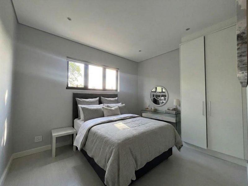 A well-maintained bedroom featuring neutral tones, built-in cupboards, and recessed downlighting, providing a clean and modern living space.