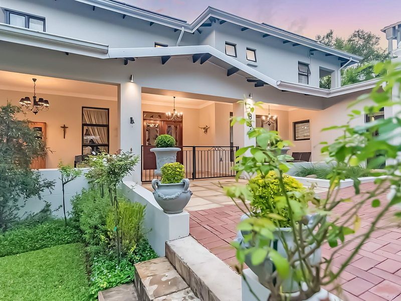 A well-maintained front entrance featuring a covered patio, brick paving, and landscaped garden elements, providing an inviting and elegant approach to the home.