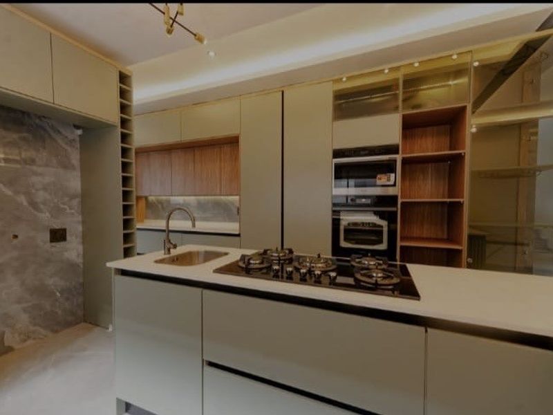 Modern kitchen featuring a central island with a gas cooktop, integrated appliances, sleek cabinetry, and stone wall finishes.