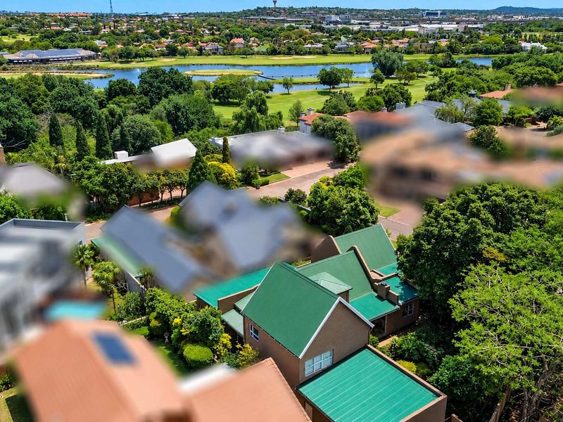 Aerial view of a residential property featuring a green metal roof and established garden within a scenic estate setting.