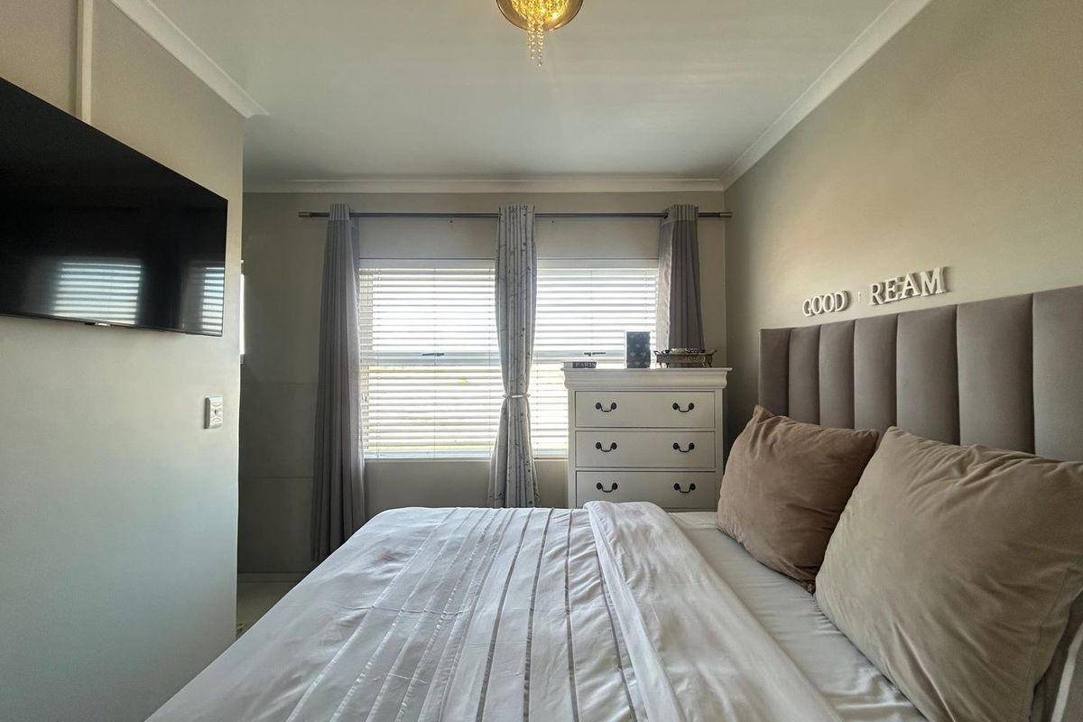 A well-maintained bedroom featuring neutral wall tones, a central light fixture, and window blinds, providing a comfortable and functional living space.