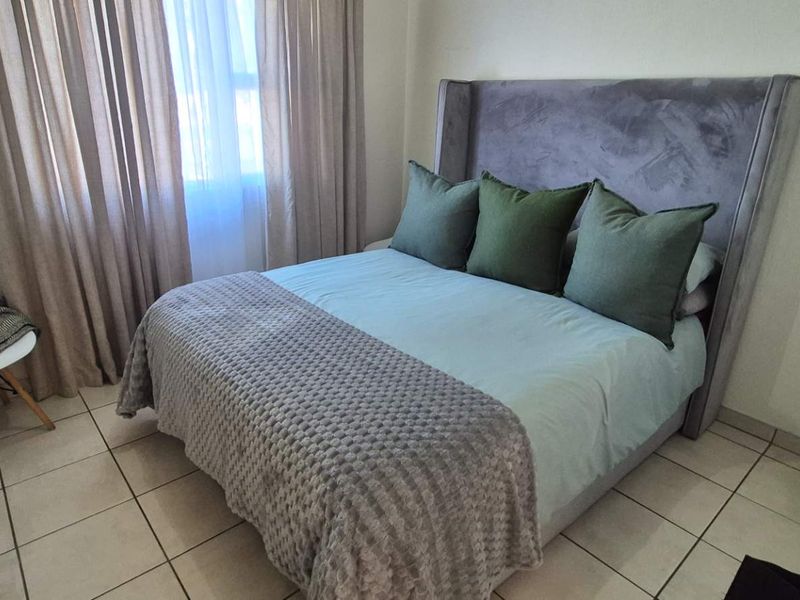 A well-maintained bedroom featuring neutral tiled flooring and a built-in cupboard, offering a clean and functional living space.