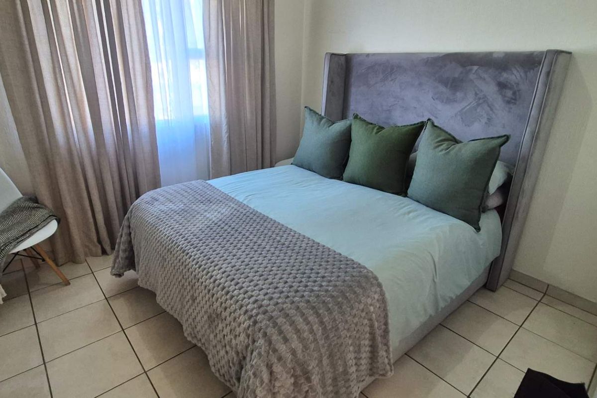 A well-maintained bedroom featuring neutral tiled flooring and a built-in cupboard, offering a clean and functional living space.