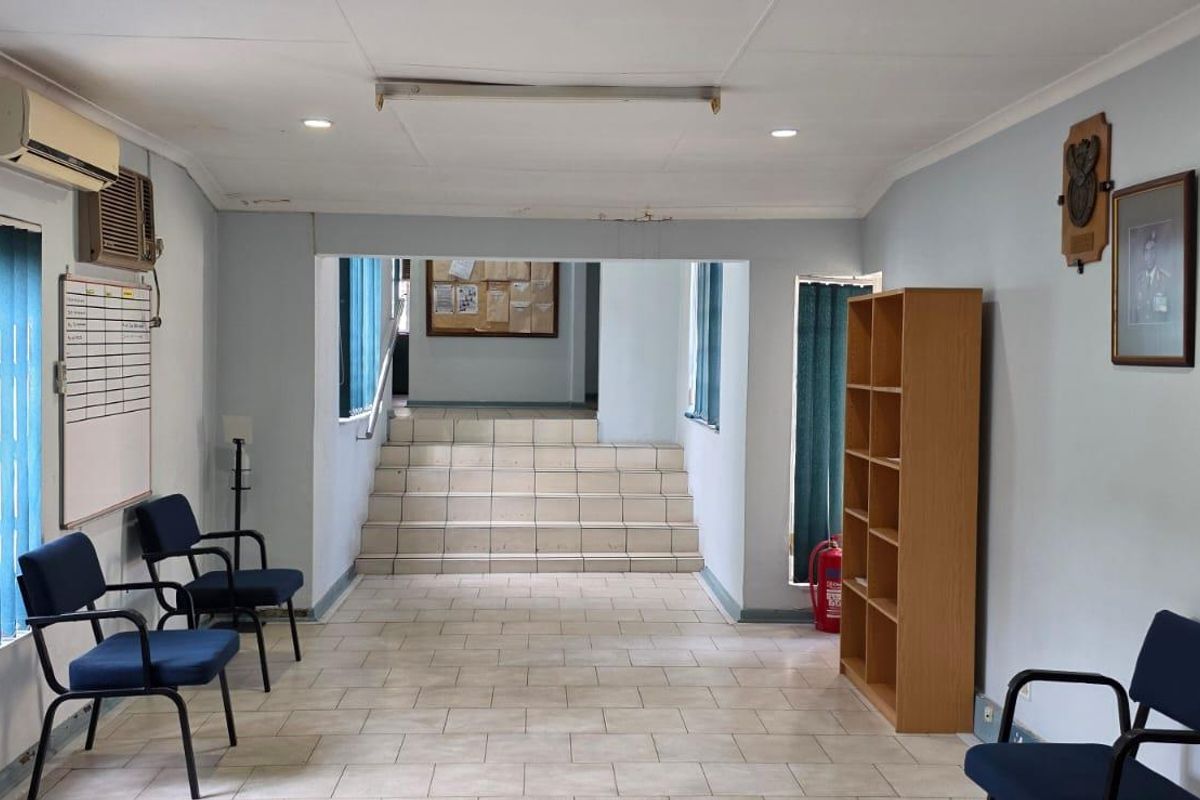 A functional office reception area featuring tiled flooring, a staircase leading to an upper level, and integrated air conditioning.