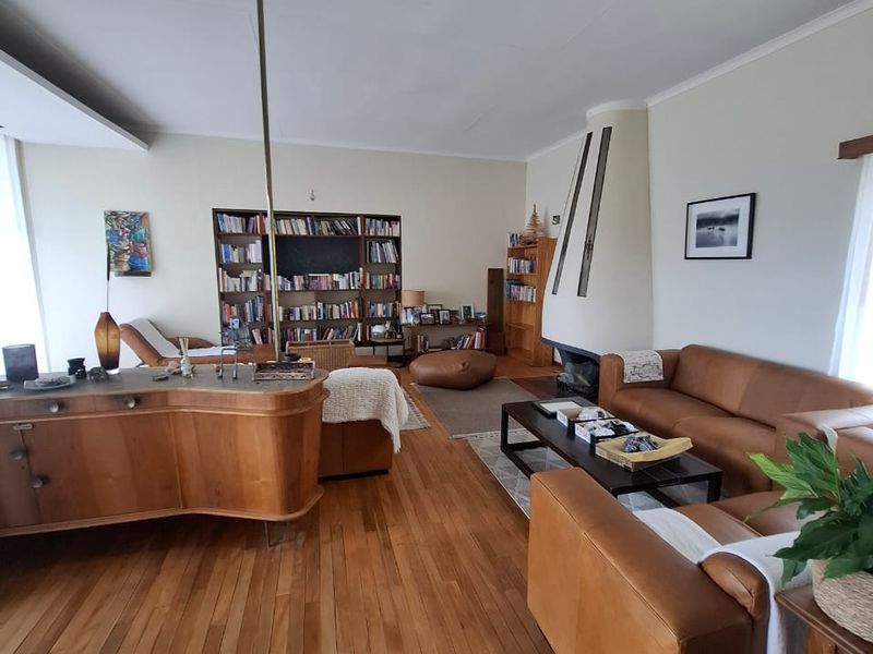 Spacious living room featuring warm hardwood flooring, a unique built-in fireplace, and integrated shelving units, offering a comfortable and inviting atmosphere.