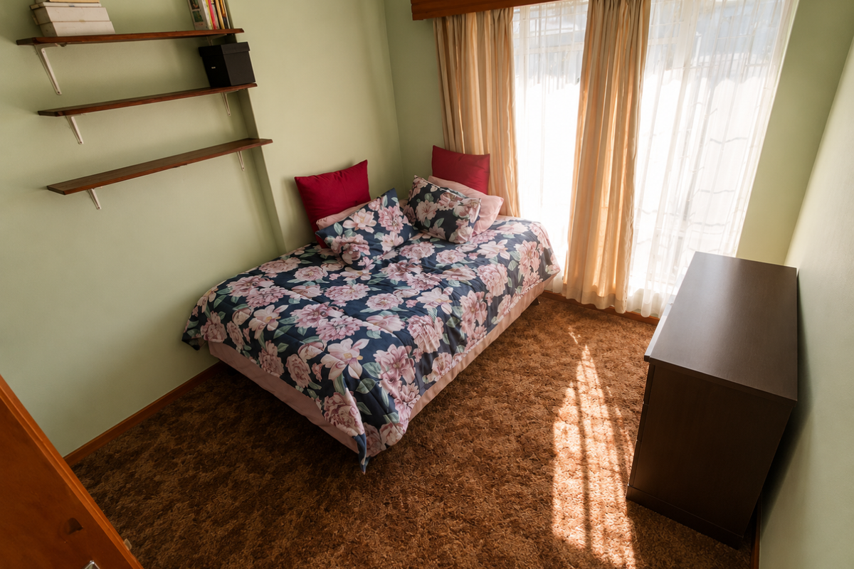 A bedroom featuring wall-mounted shelving, carpet flooring, and large windows with curtains, offering a functional space with potential for cosmetic updates.