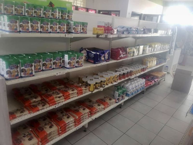 A retail space featuring rows of metal shelving units stocked with various grocery products and finished with tiled flooring.