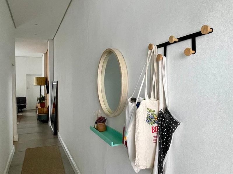 A bright and clean hallway featuring tiled flooring, a wall-mounted coat rack, and a small decorative shelf.