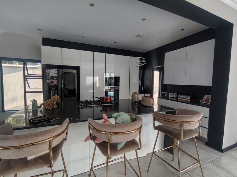 Modern kitchen featuring a large central island with a stone countertop, integrated cabinetry, built-in oven, and gas hob, finished with contemporary lighting.