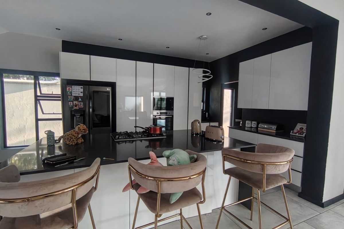 Modern kitchen featuring a large central island with a stone countertop, integrated cabinetry, built-in oven, and gas hob, finished with contemporary lighting.