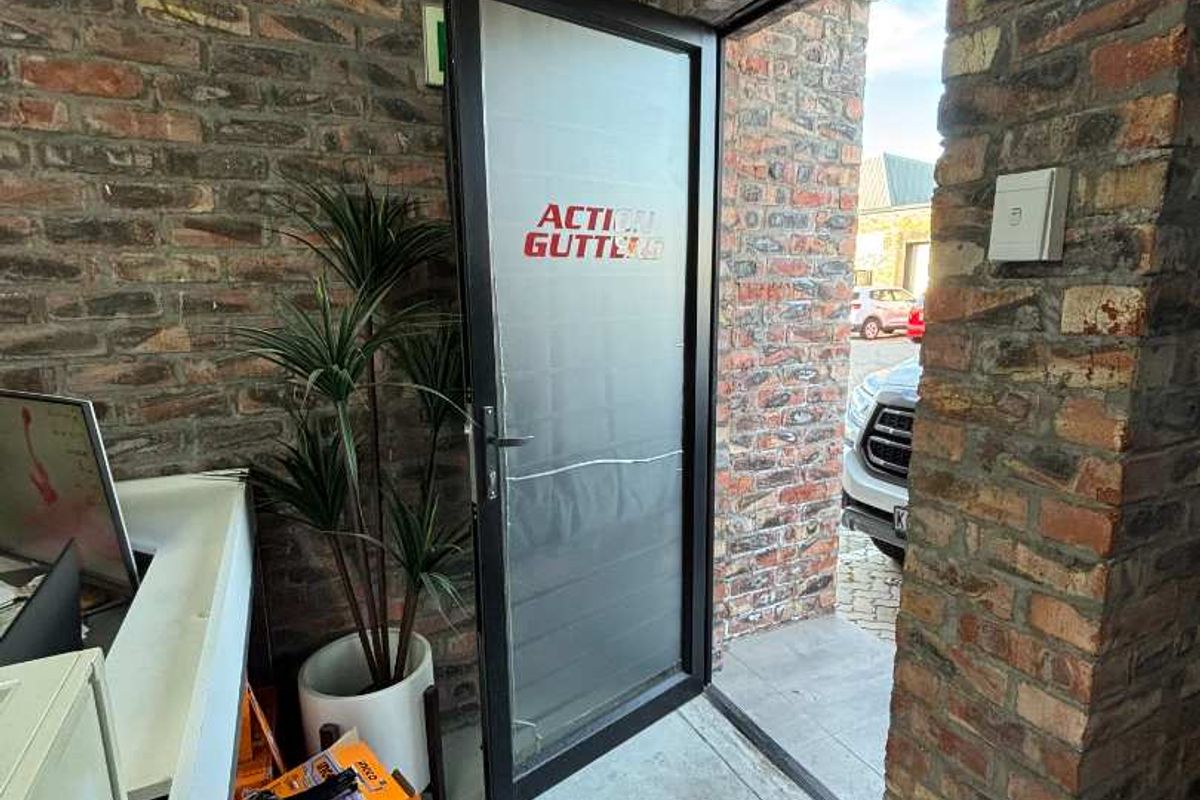 Entrance area featuring exposed brick walls and an aluminium framed glass door with branding.
