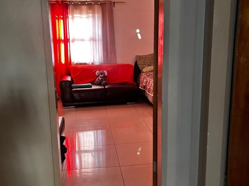 A view through a doorway into a living area featuring tiled flooring and natural light from a window.