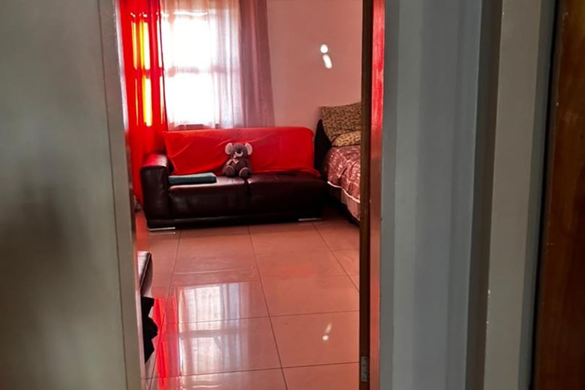 A view through a doorway into a living area featuring tiled flooring and natural light from a window.