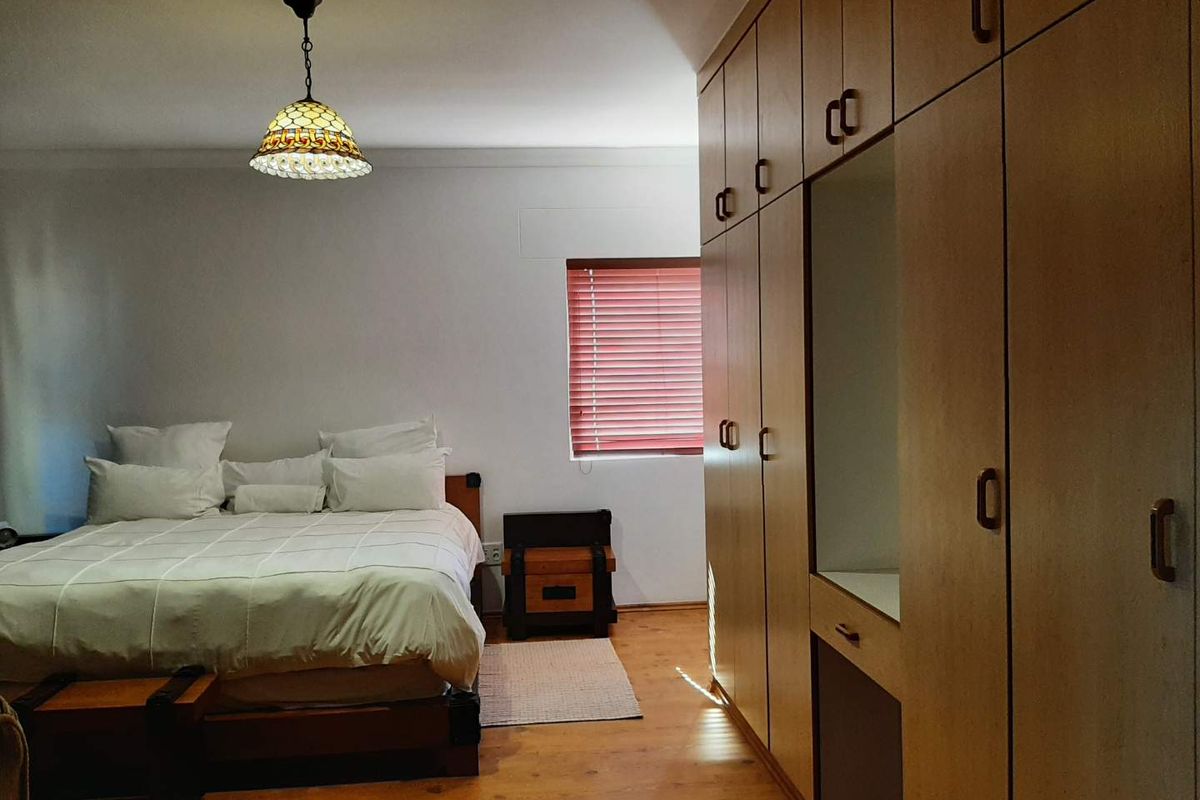 A bedroom featuring built-in wooden cabinetry with integrated vanity space, wooden flooring, and a decorative pendant light fixture.