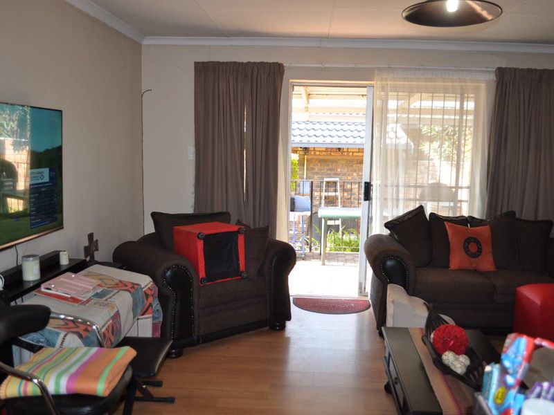 A living room featuring laminate flooring and a sliding glass door providing access to an outdoor patio area.