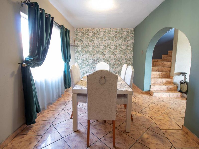 Dining room featuring tiled flooring, a decorative wallpaper accent wall, and an arched entryway leading to a staircase.