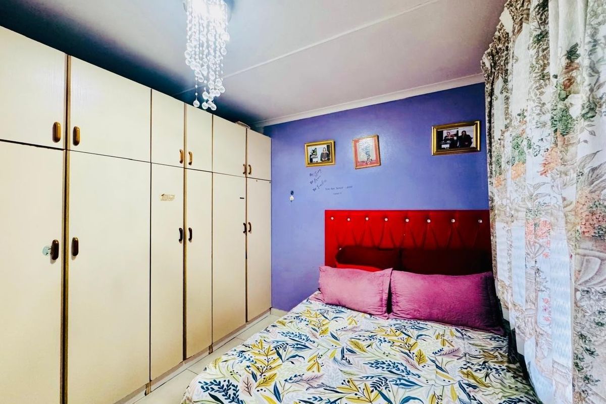 A bedroom featuring built-in cupboards, tiled flooring, and a decorative crystal chandelier.