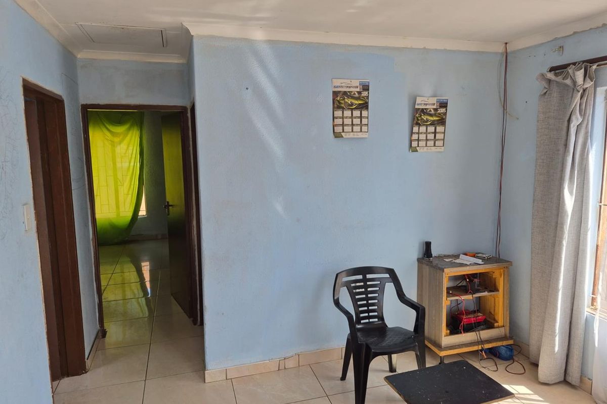A living area featuring tiled flooring and access to an adjacent room, showing signs of wear and requiring cosmetic updates.
