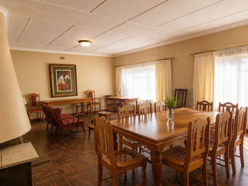 Spacious living and dining area featuring classic parquet flooring, a built-in fireplace, and large windows that provide ample natural light.