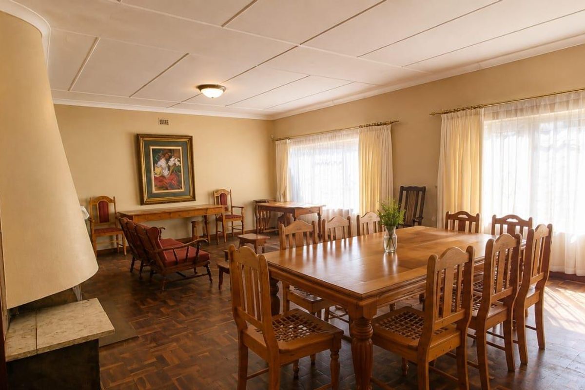 Spacious living and dining area featuring classic parquet flooring, a built-in fireplace, and large windows that provide ample natural light.