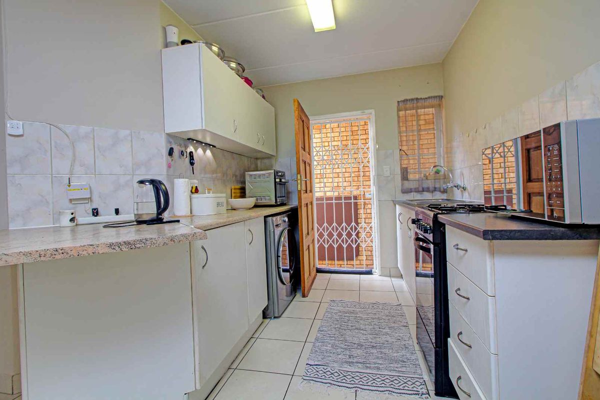 Functional kitchen featuring laminate countertops, built-in cabinetry, tiled flooring, and direct access to an exterior security gate.