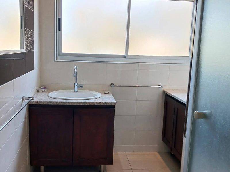 A clean and functional bathroom featuring a vanity cabinet with a stone countertop, basin, and tiled finishes throughout.
