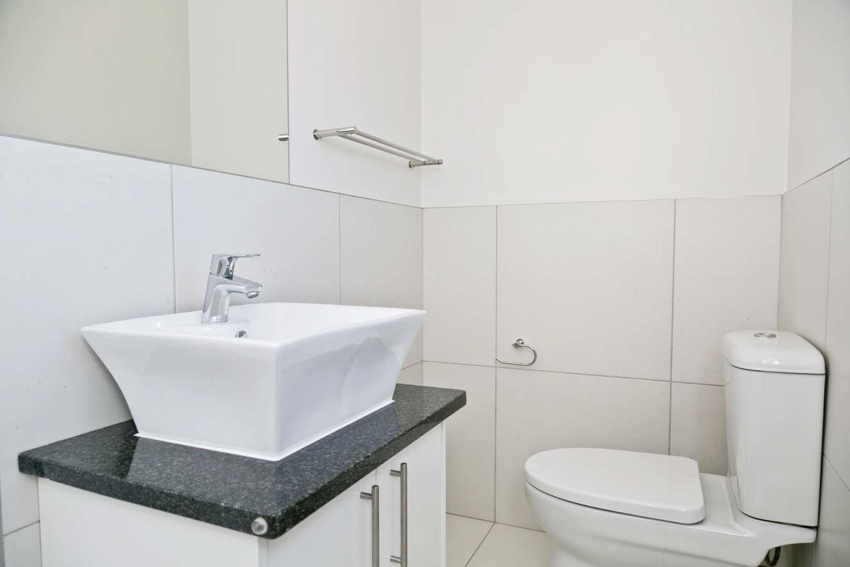 A clean and modern bathroom featuring a contemporary vessel sink on a granite vanity, complemented by neutral wall tiling and a wall-mounted mirror.