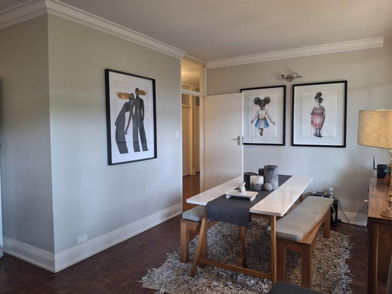 A well-maintained dining area featuring classic parquet flooring, crown molding, and neutral wall finishes, providing a clean and inviting space for meals.