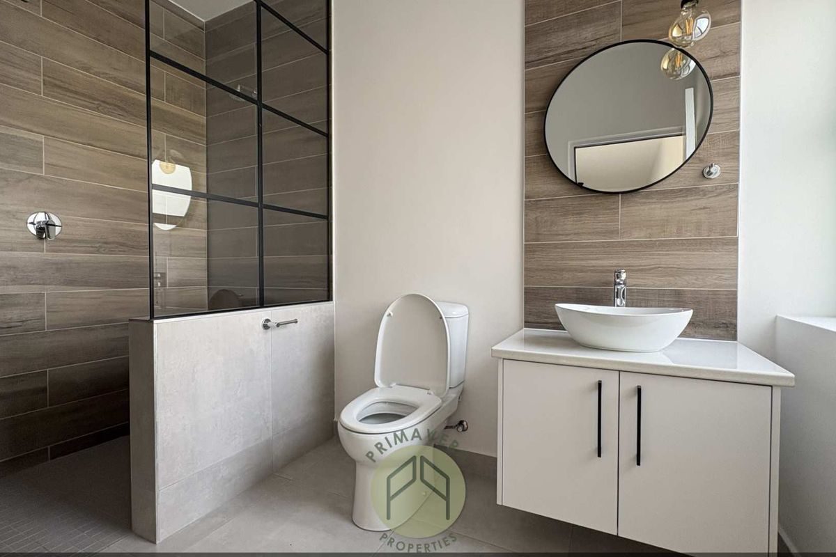 Modern bathroom featuring a walk-in shower with black-framed glass partition, floating vanity with vessel sink, and contemporary wood-look wall tiling.