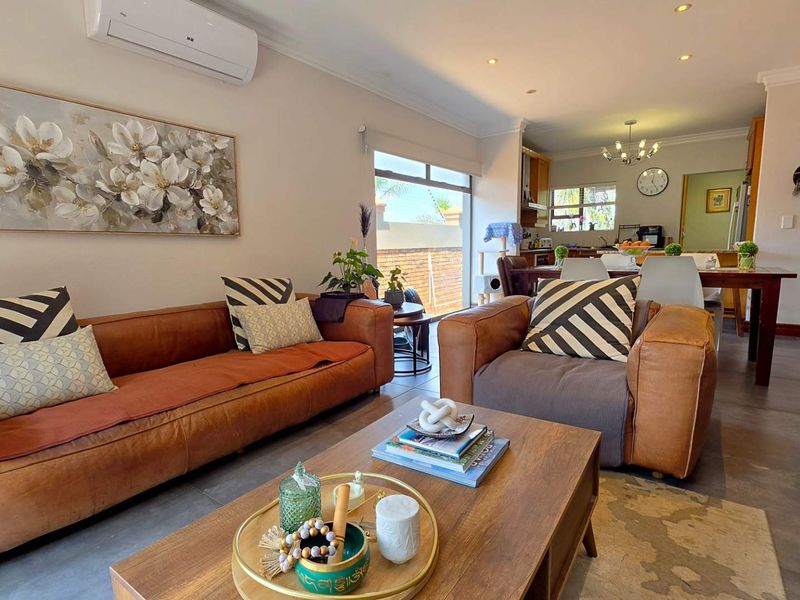 An open-plan living and dining area featuring tiled flooring, recessed lighting, and a split-system air conditioner, flowing into a functional kitchen space.