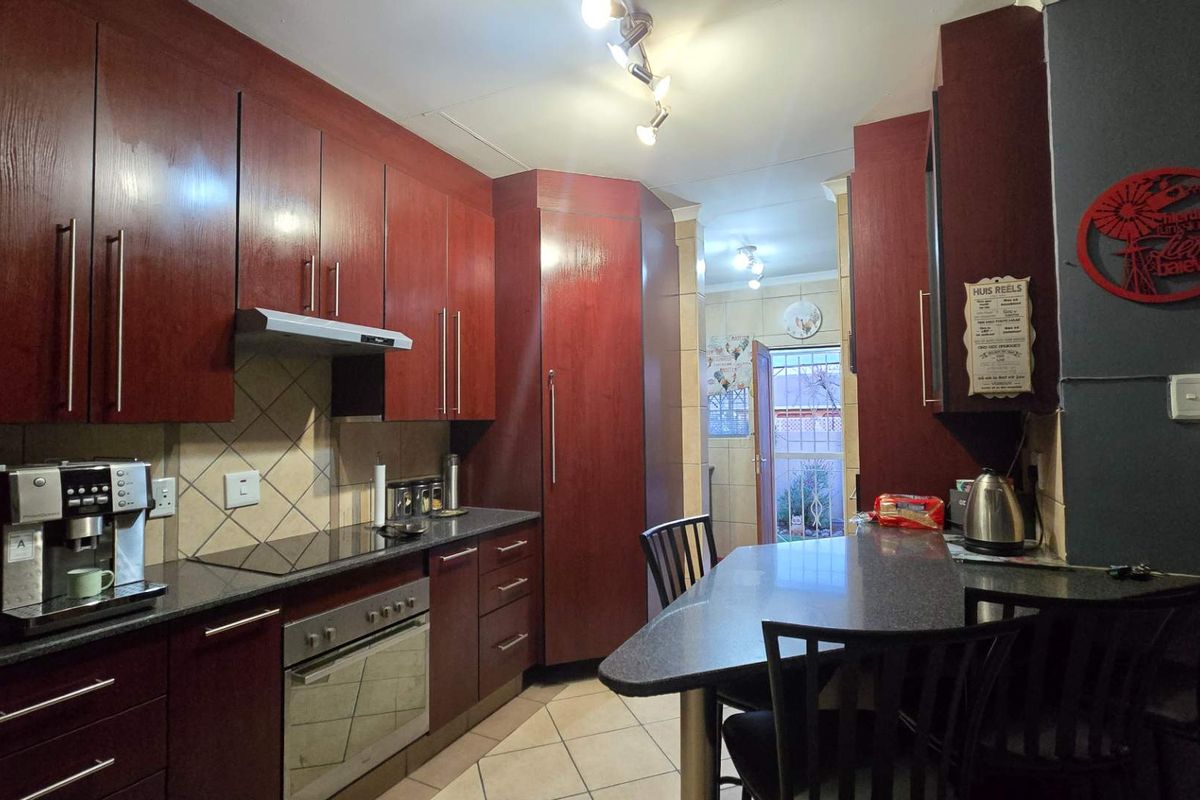 A functional kitchen featuring dark wood cabinetry, granite countertops, a built-in oven with hob, and a breakfast bar area.
