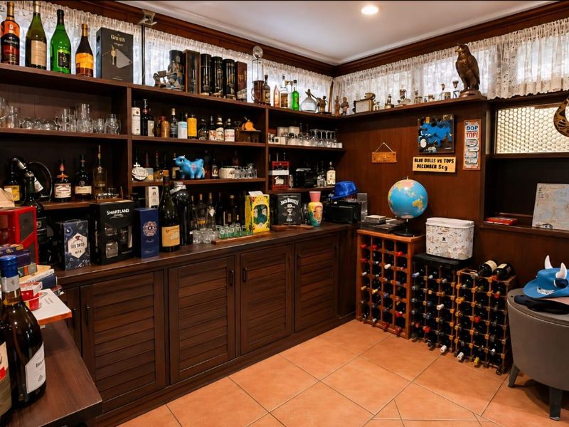 A dedicated home bar area featuring extensive built-in timber cabinetry, open shelving for display, and tiled flooring.