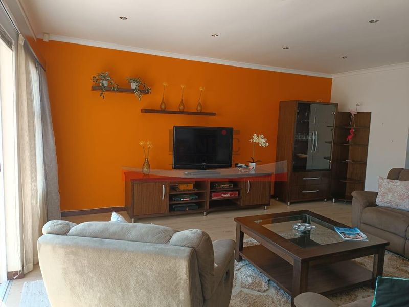 A living room featuring laminate flooring, recessed downlights, and a sliding glass door leading to an outdoor area.