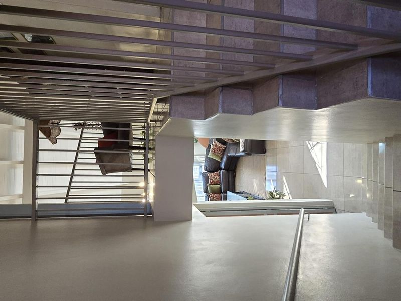 A view looking down a staircase featuring tiled steps, a metal balustrade, and a handrail, connecting the levels of the townhouse.