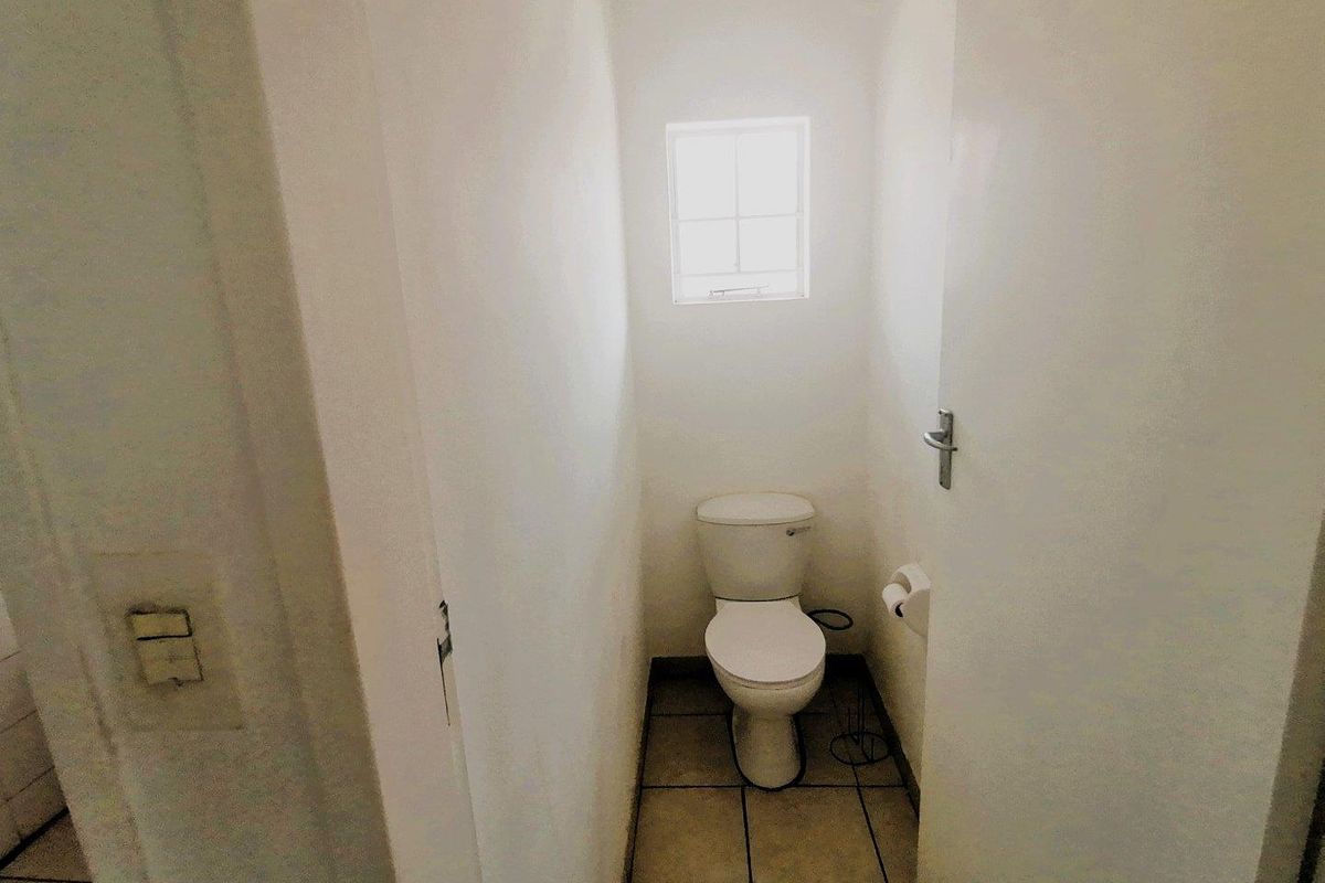 A compact guest toilet featuring tiled flooring, a standard white toilet suite, and a small window for natural ventilation.