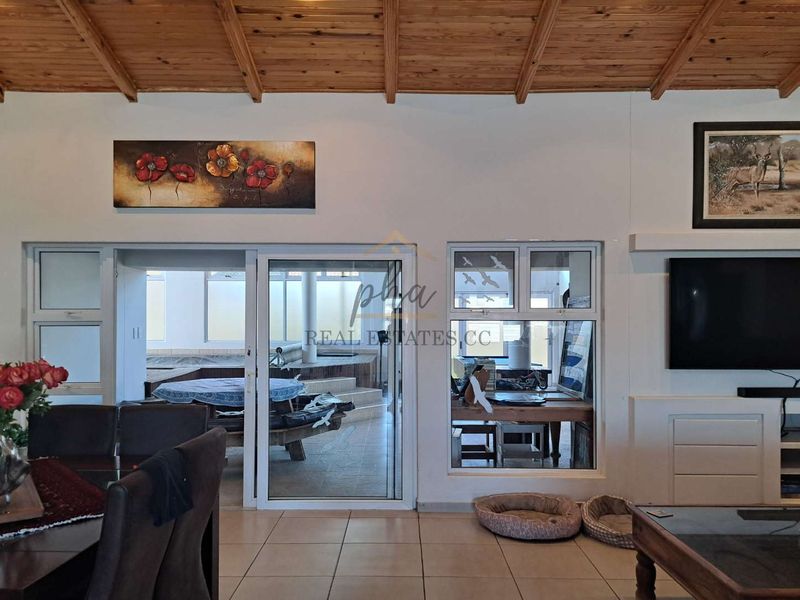 Spacious living area featuring an exposed timber beam ceiling, tiled flooring, and large sliding glass doors providing access to an adjacent patio space.