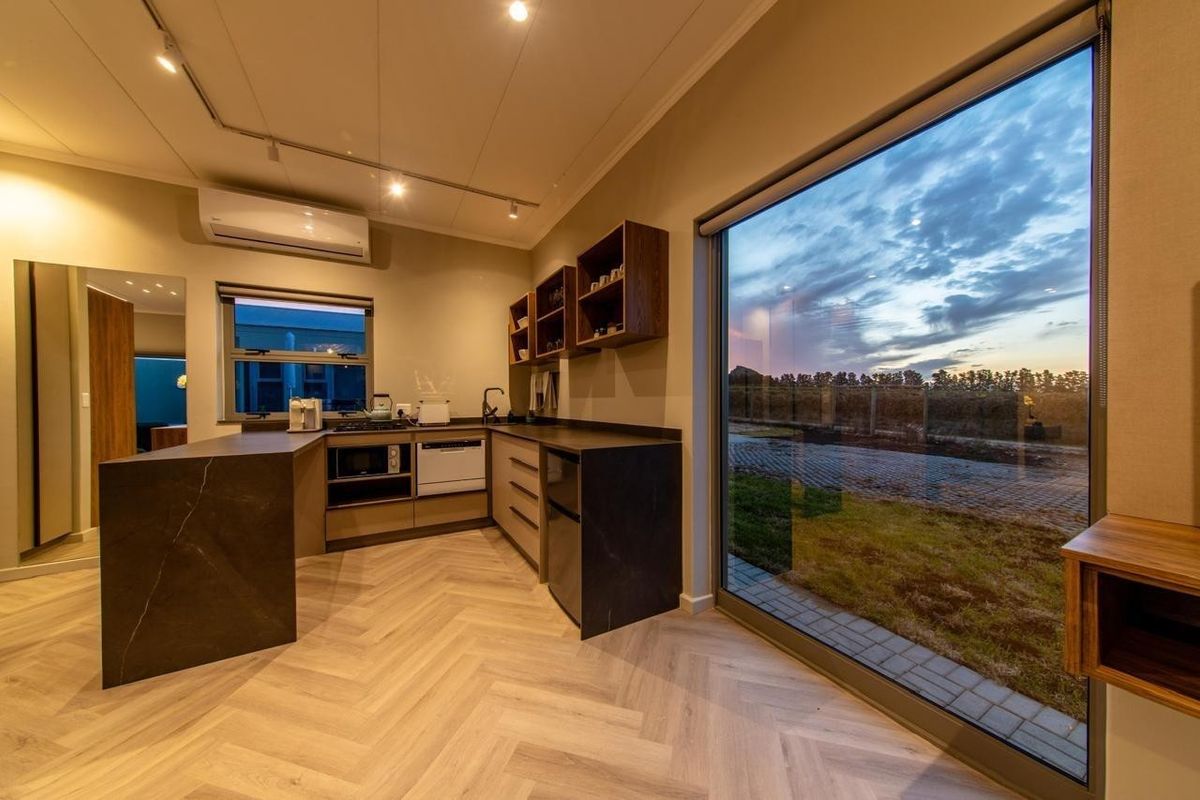 Modern kitchenette featuring dark stone countertops, herringbone flooring, built-in cabinetry, and large floor-to-ceiling windows with exterior views.