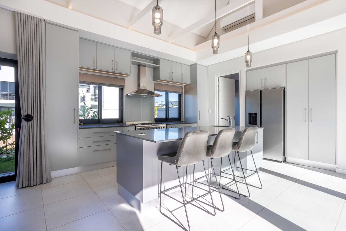 Modern kitchen featuring a central island, sleek cabinetry, high-end built-in appliances, and a vaulted ceiling with contemporary pendant lighting.