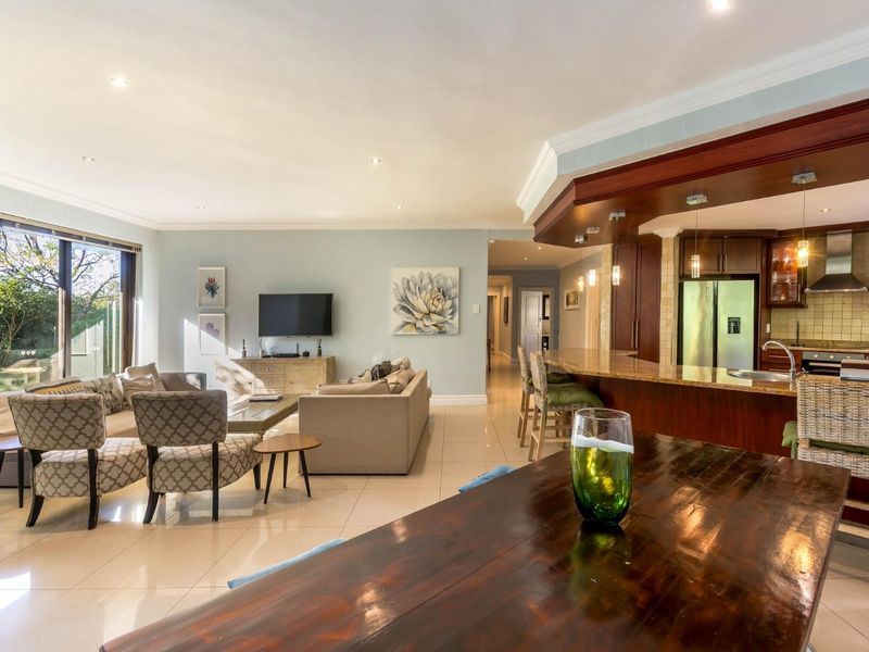 Spacious open-plan living area featuring a modern kitchen with granite countertops, breakfast bar, and seamless flow to the outdoor garden through sliding glass doors.