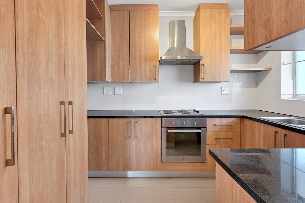 Modern kitchen featuring light wood cabinetry, granite countertops, stainless steel appliances, and tiled flooring in a clean, functional layout.