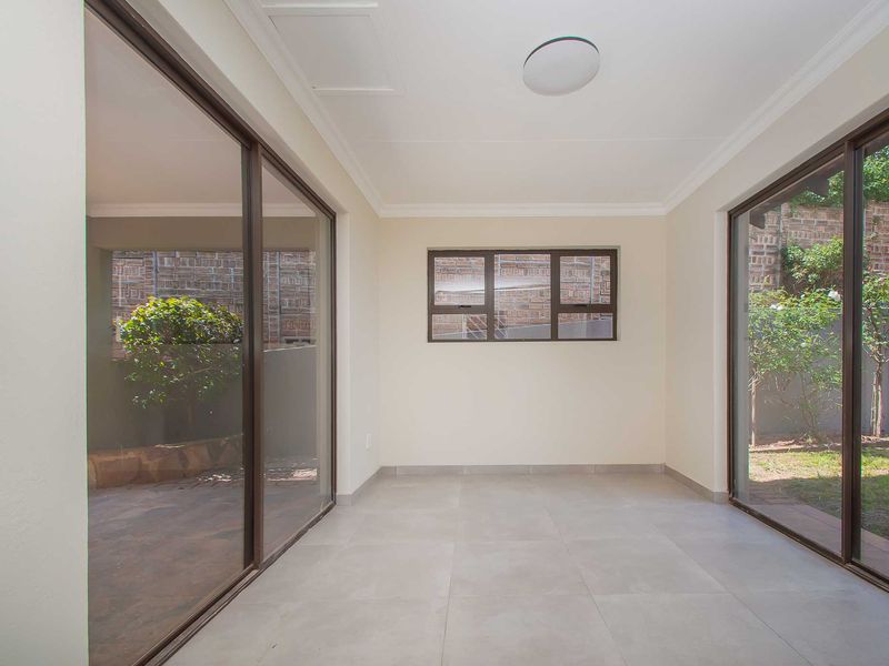 A bright, empty living area featuring large sliding glass doors that provide ample natural light and direct access to the outdoor garden space.
