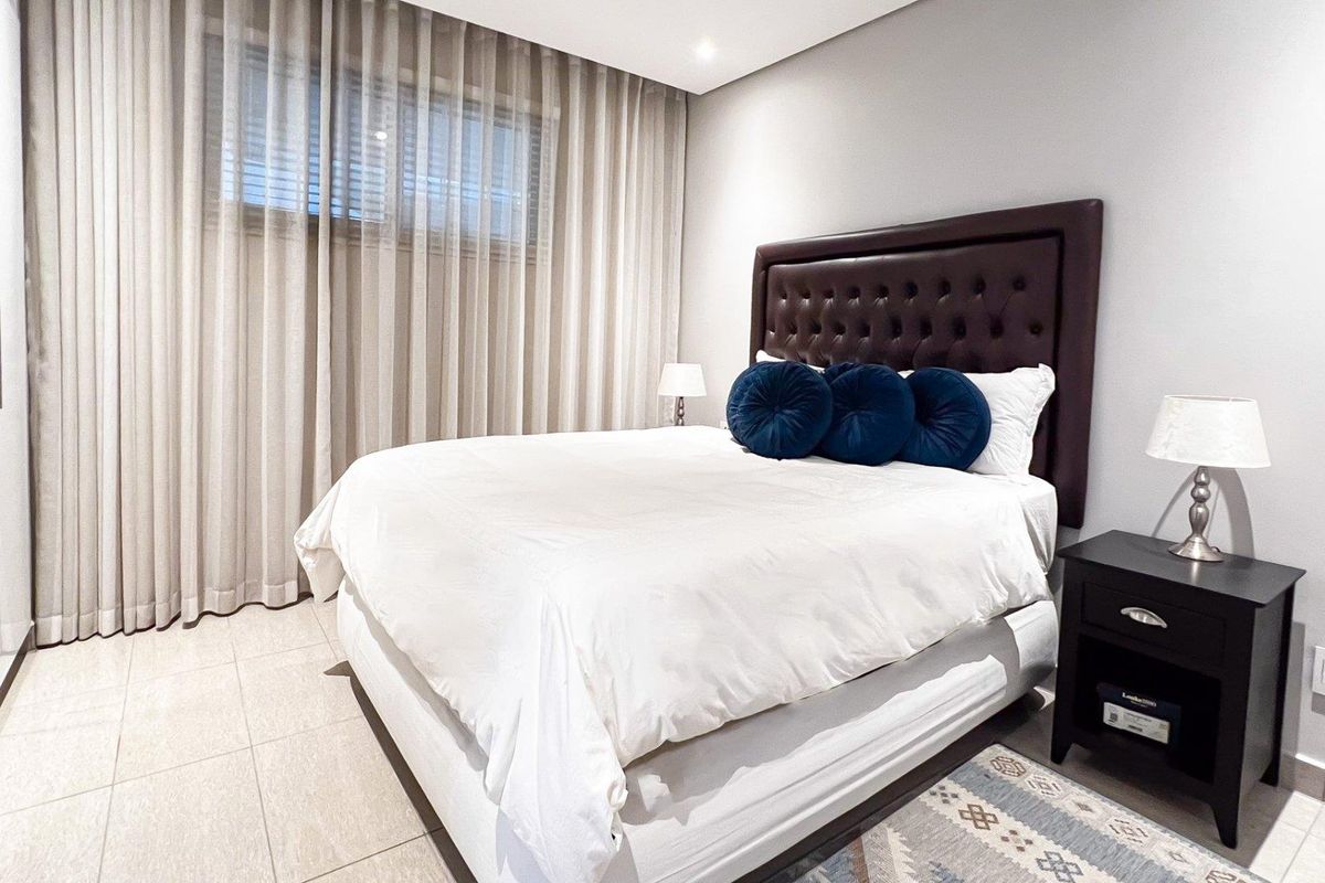 A well-maintained bedroom featuring tiled flooring, recessed ceiling lighting, built-in wardrobes, and floor-to-ceiling window curtains.