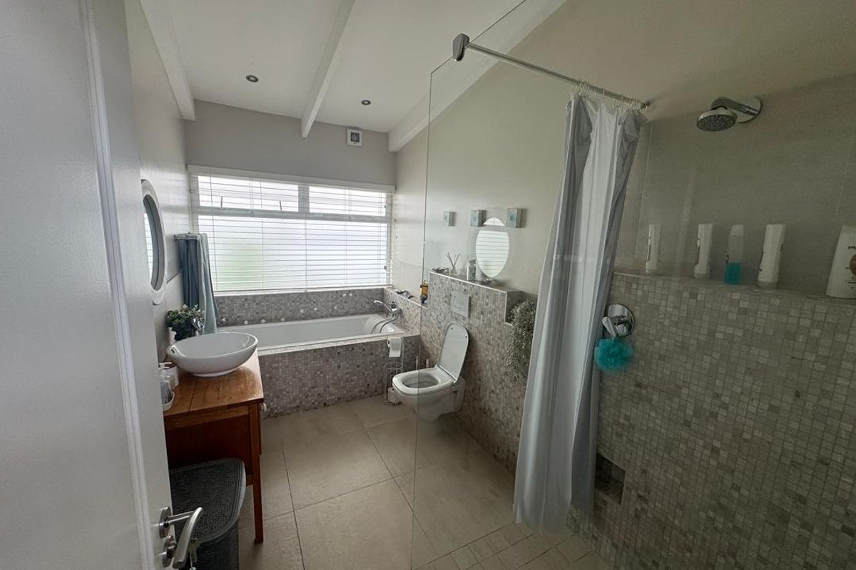 A functional bathroom featuring a glass-enclosed walk-in shower, a built-in bathtub with mosaic tile surround, and a wall-mounted toilet.